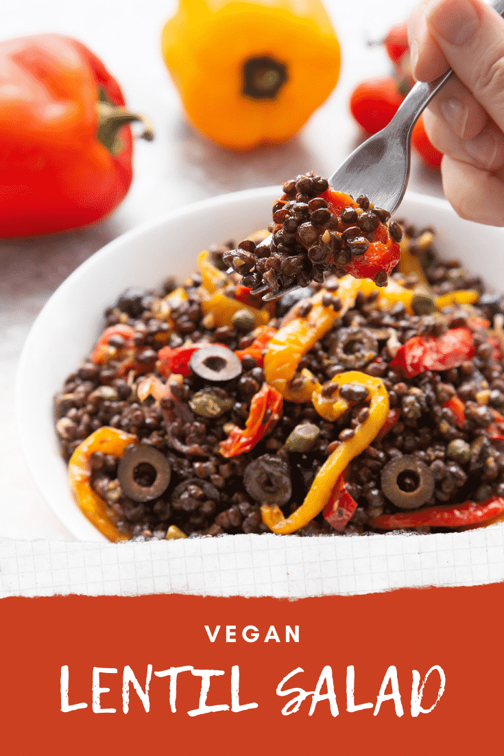 Vegan lentil salad served in a white shallow bowl. A hand with a fork delves in. Caption reads: vegan lentil salad