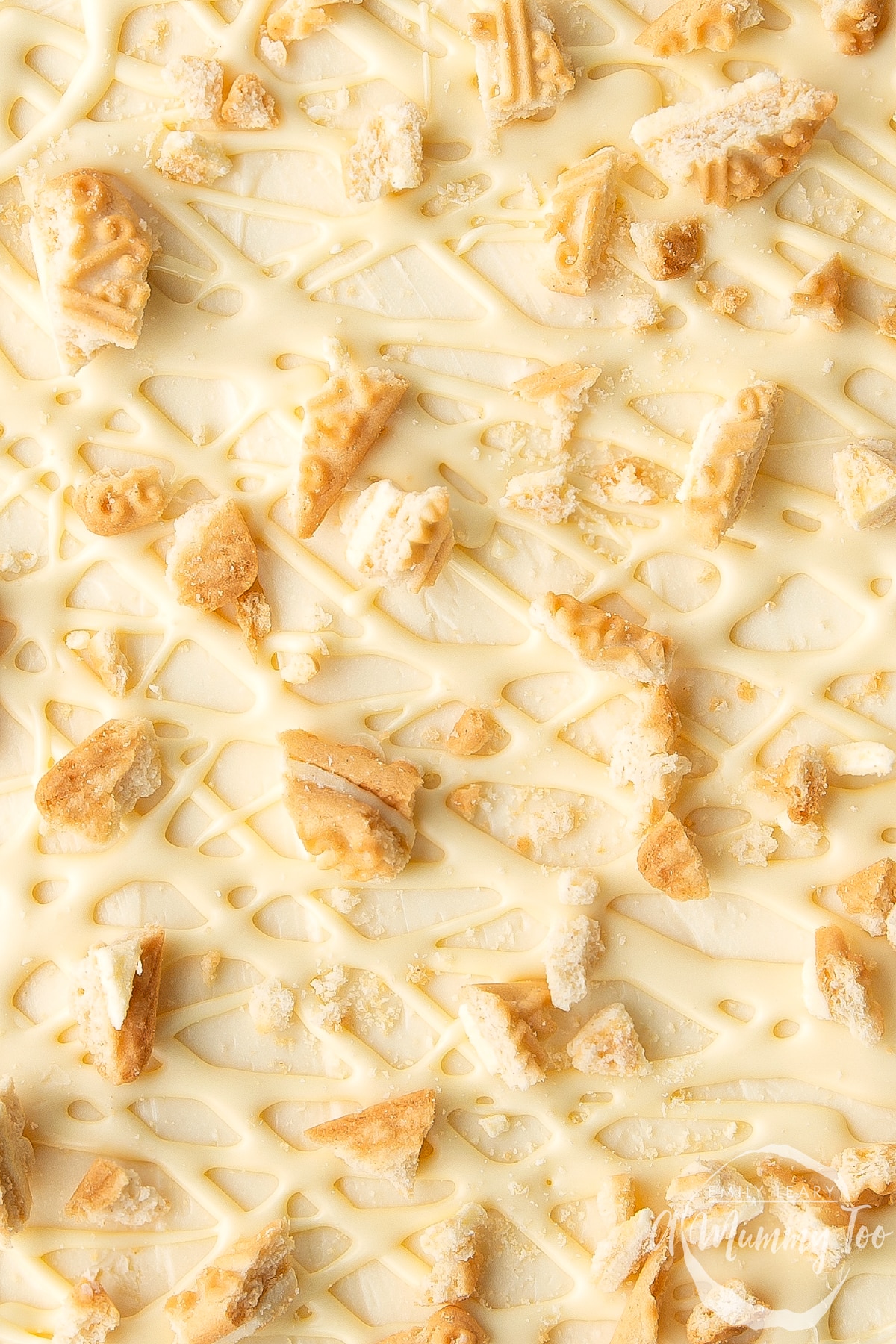 Overhead shot of the top of a cheesecake with drizzled sauce and crushed custard cream biscuits