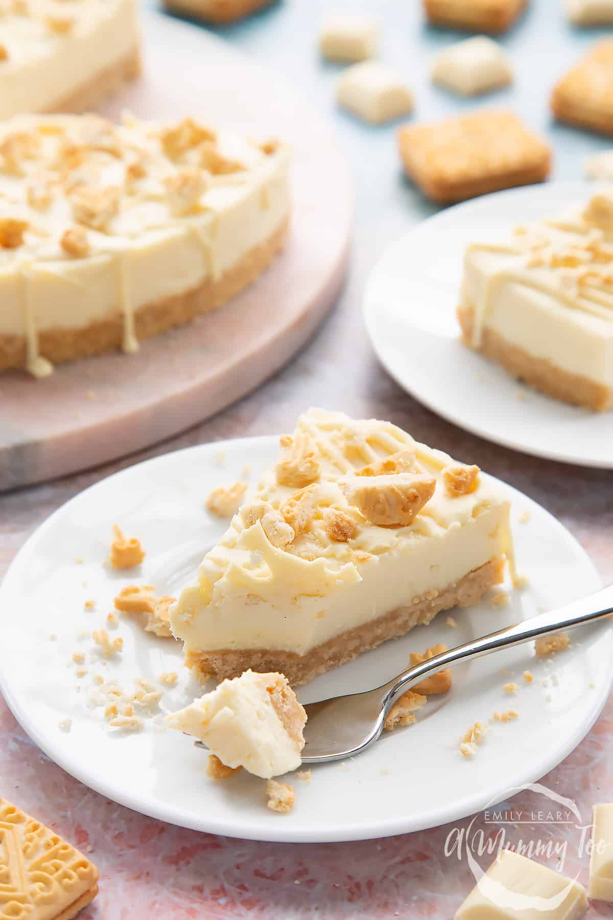 Front view shot of a piece of cheesecake with a fork on a white plate