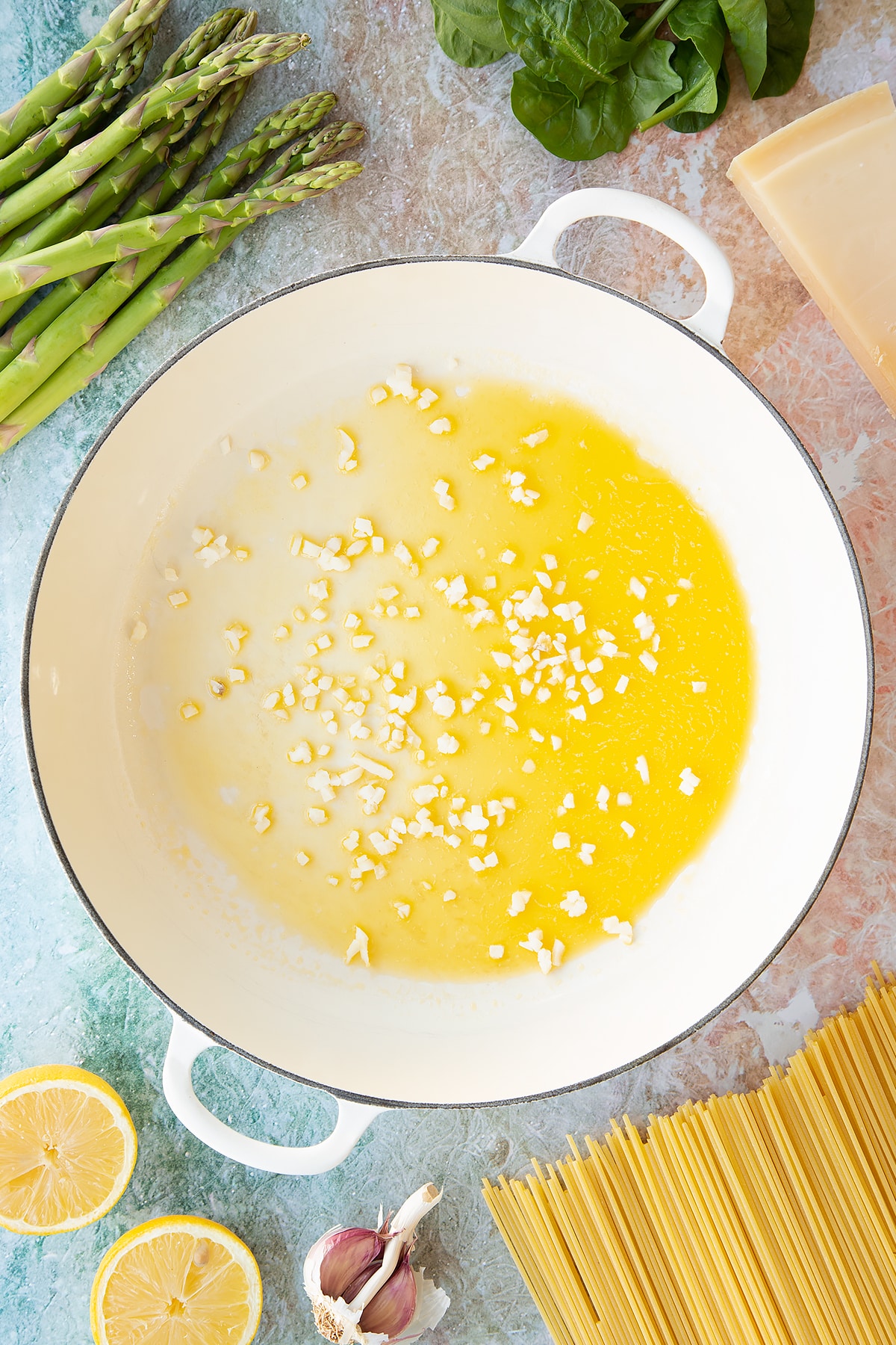Melted butter, olive oil and chopped garlic in a large, shallow saucepan. Ingredients to make summer spaghetti surround the pan.