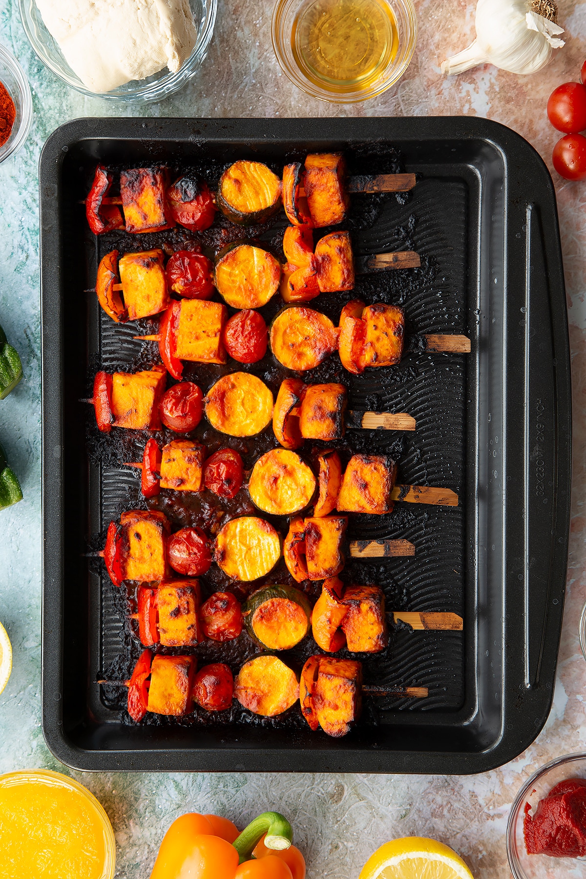Cooked tofu skewers lined up on a baking tray.