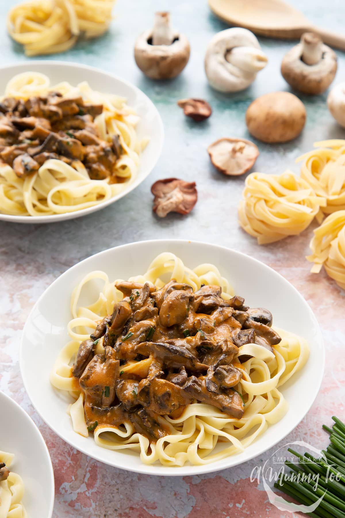 side view of Creamy vegan mushroom stroganoff on a bed of taglietelle with ingredients in the background