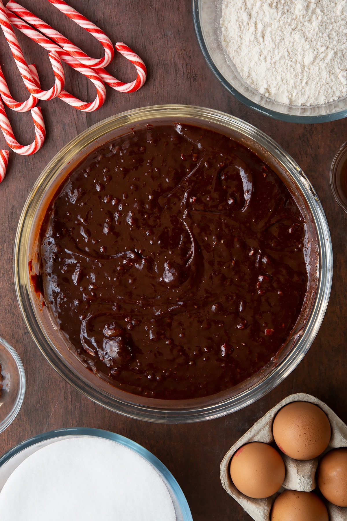 Candy cane brownie batter in a glass bowl. Ingredients to make Candy cane brownies surround the bowl.