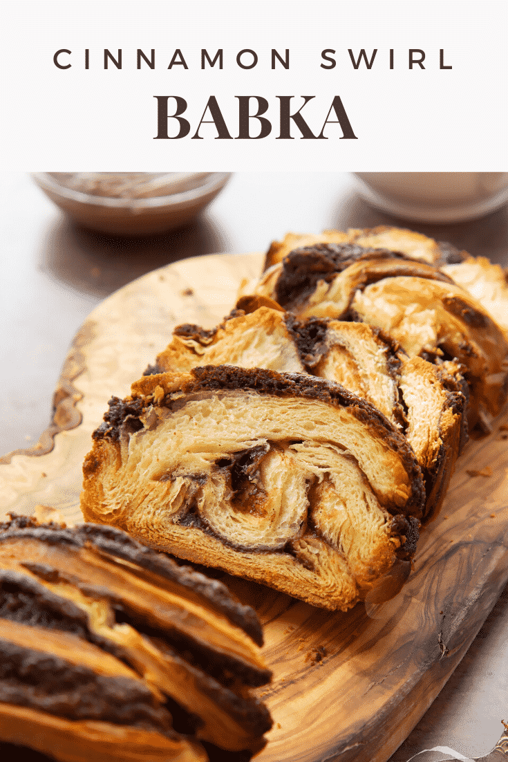 Slices of cinnamon swirl babka on a wooden board. Caption reads: cinnamon swirl babka