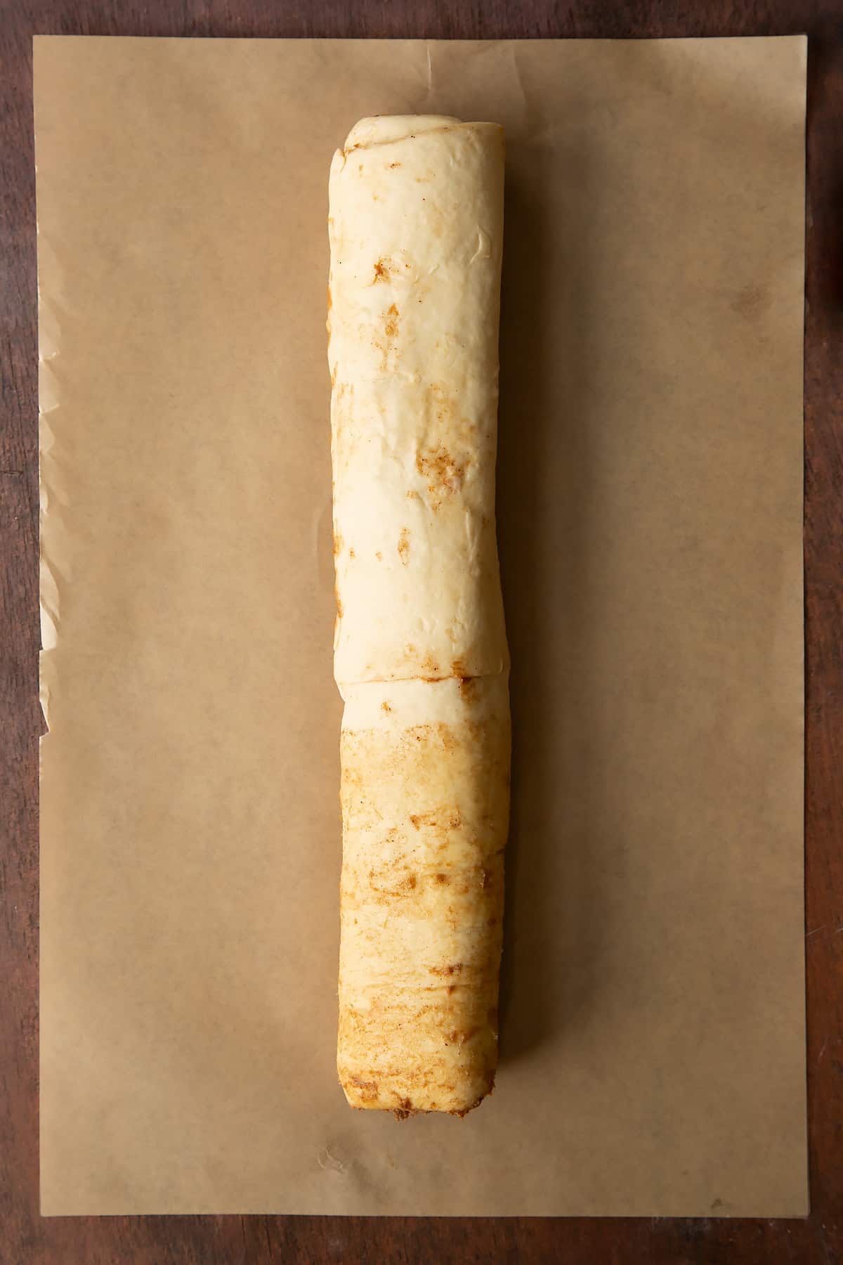 Cinnamon swirl dough rolled along the length to create a long sausage.
