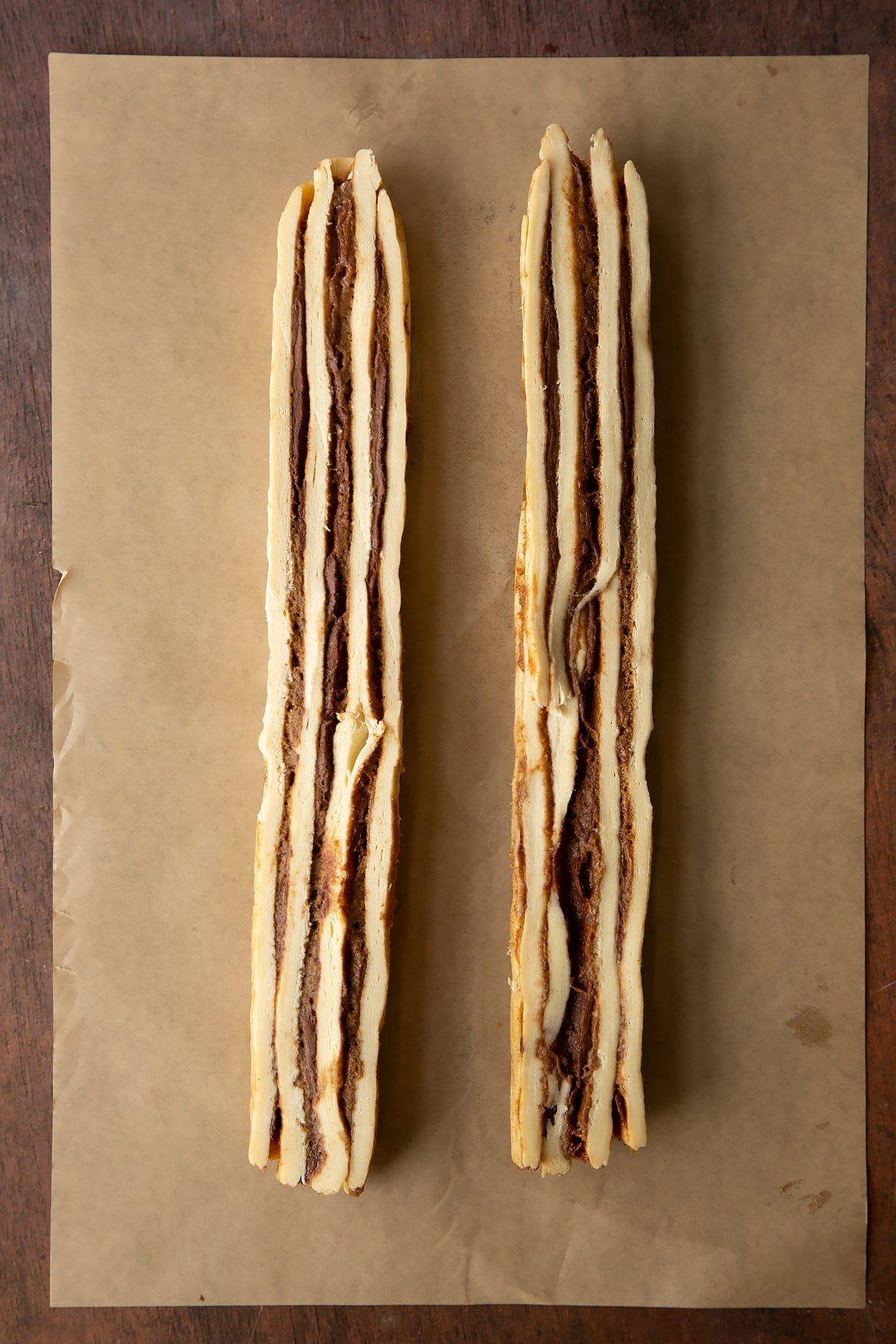 Cinnamon swirl dough rolled along the length to create a long sausage, then sliced down the length to create two striped pieces.