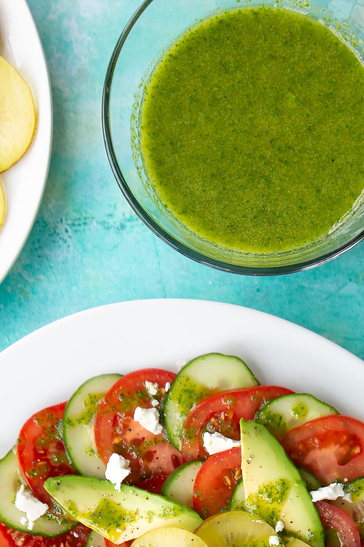 Basil oil in a small glass bowl beside a kiwi feta salad.