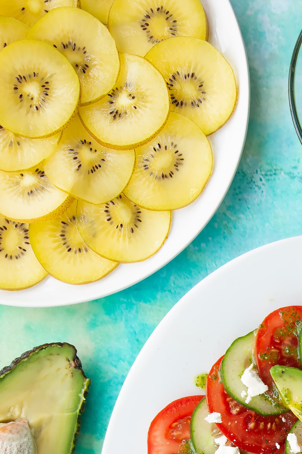 Sliced golden kiwis on a white plate beside a kiwi feta salad.
