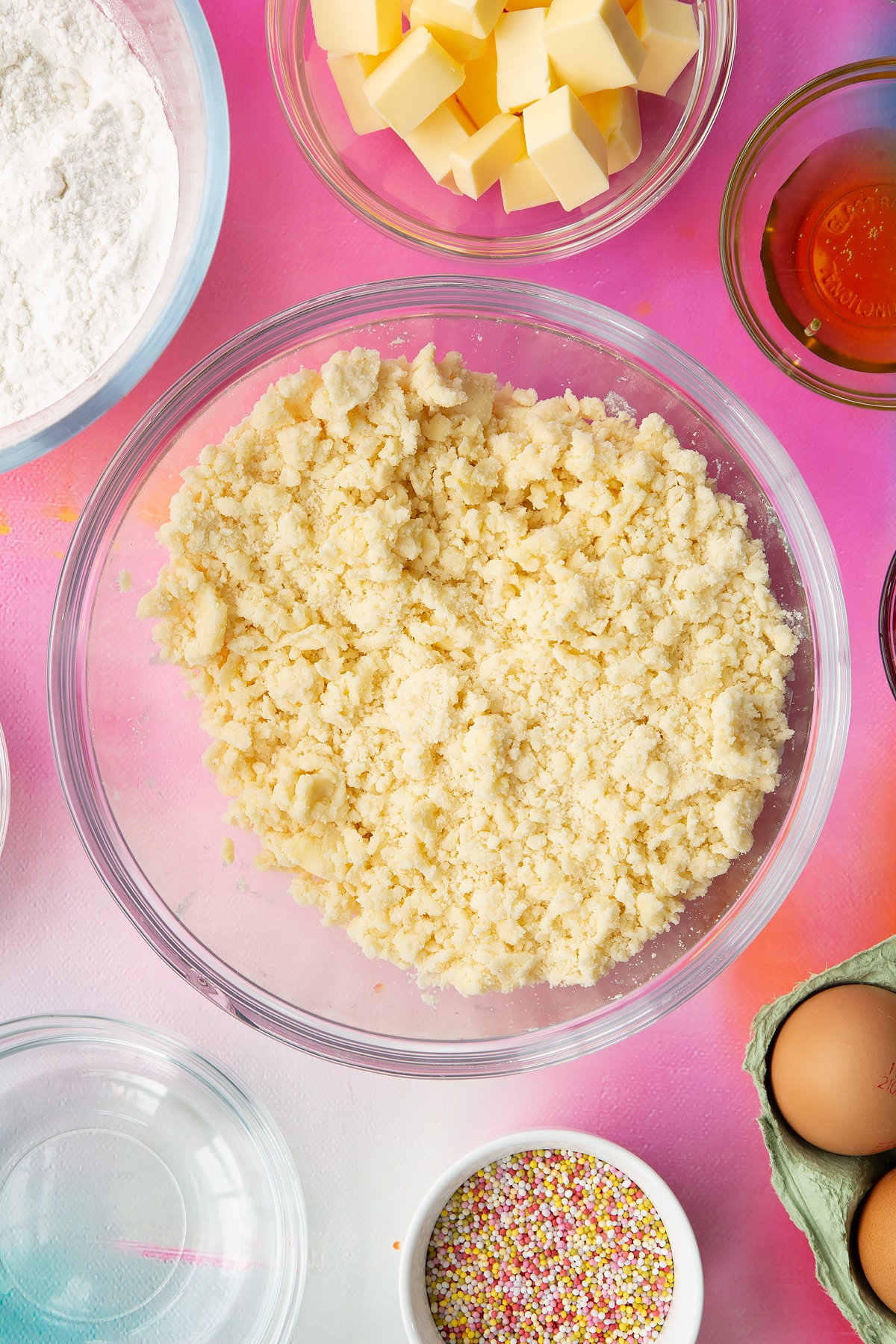 Butter, gluten free flour and sugar rubbed together in a glass mixing bowl. Ingredients to make gluten free pop tarts surround the bowl.