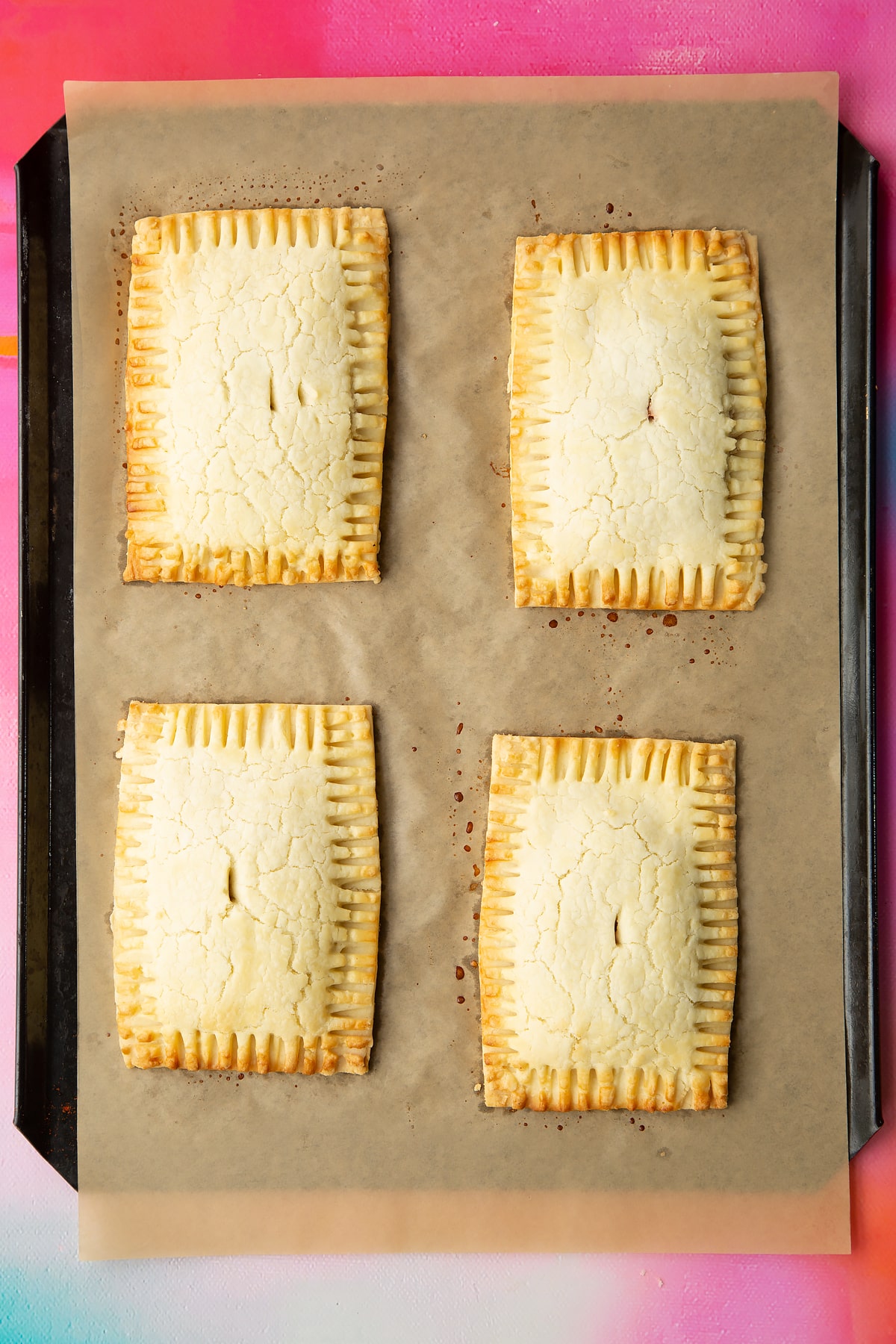 Four freshly baked gluten free pop tarts on a baking tray lined with baking paper.