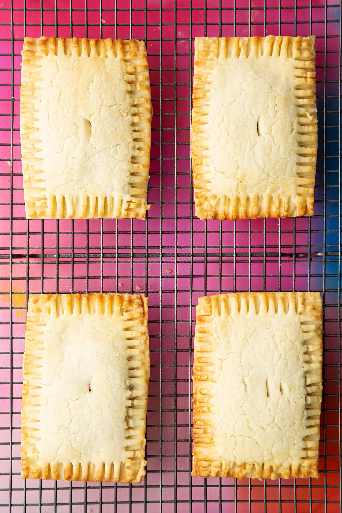 Four freshly baked gluten free pop tarts on a wire cooling rack.