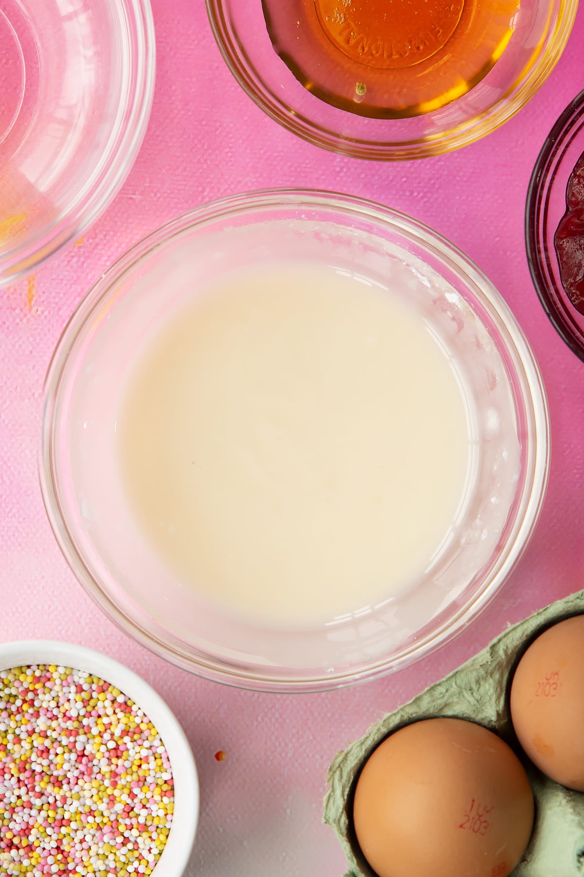 White icing in a small bowl. Ingredients to make gluten free pop tarts surround the bowl.