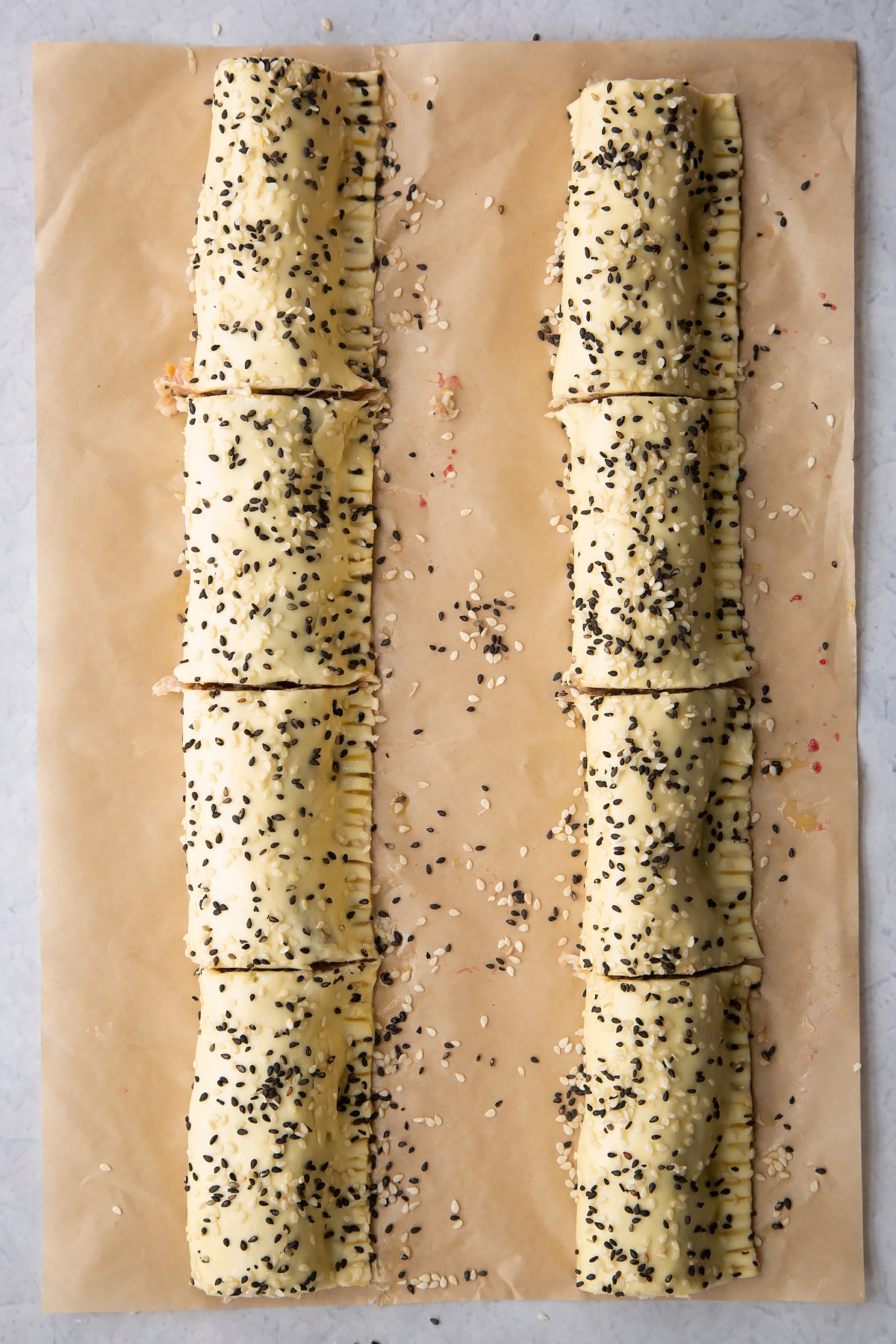 Two lengths of festive sausage meat wrapped in puff pastry , scattered with sesame seeds and cut into 8
in total.