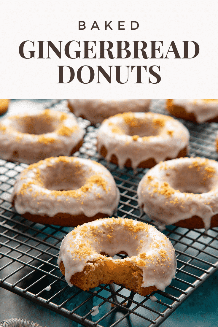 Baked gingerbread donuts with a lemon glaze on a wire cooling rack. One has a bite out of it. Caption reads: Baked gingerbread donuts.