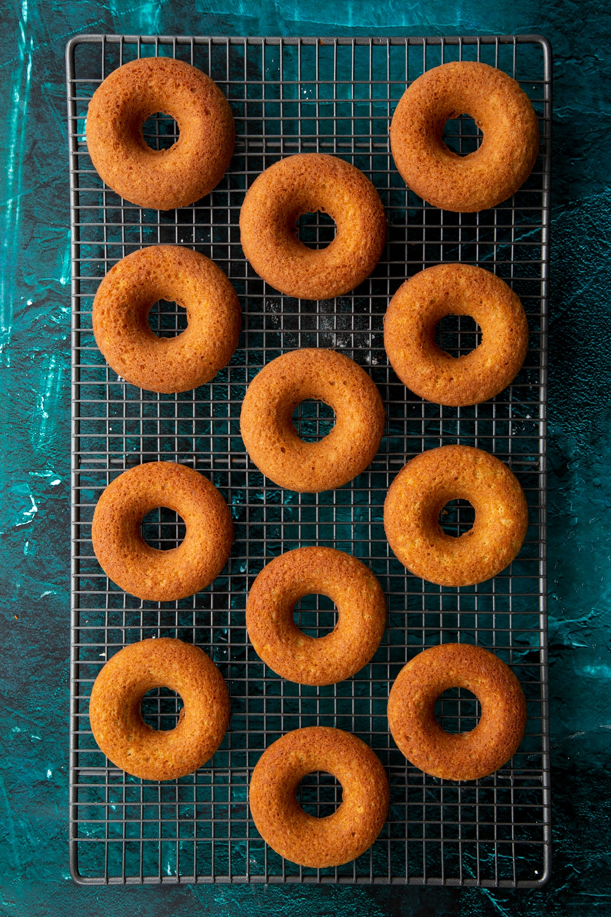 Freshly baked gingerbread donuts on a wire cooling rack.