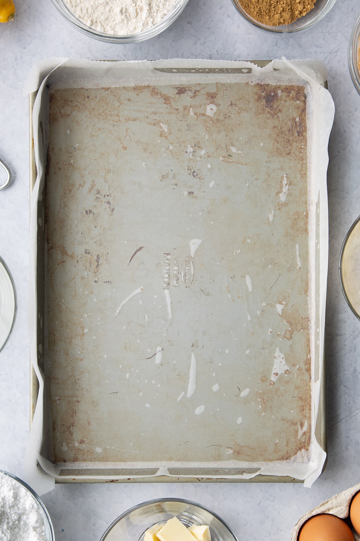 Swiss roll tray, greased and lined with baking paper. Ingredients to make Gingerbread Swiss roll surround the tray.