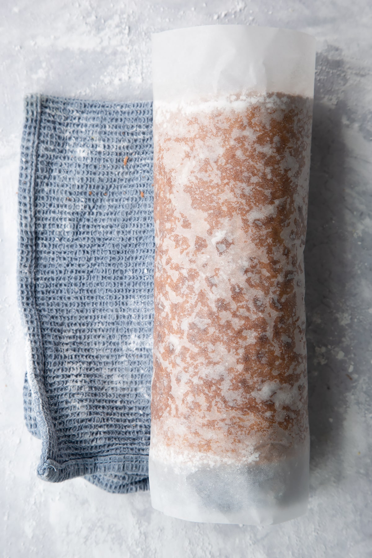 Baked gingerbread Swiss roll sponge, rolled up with a tea towel.