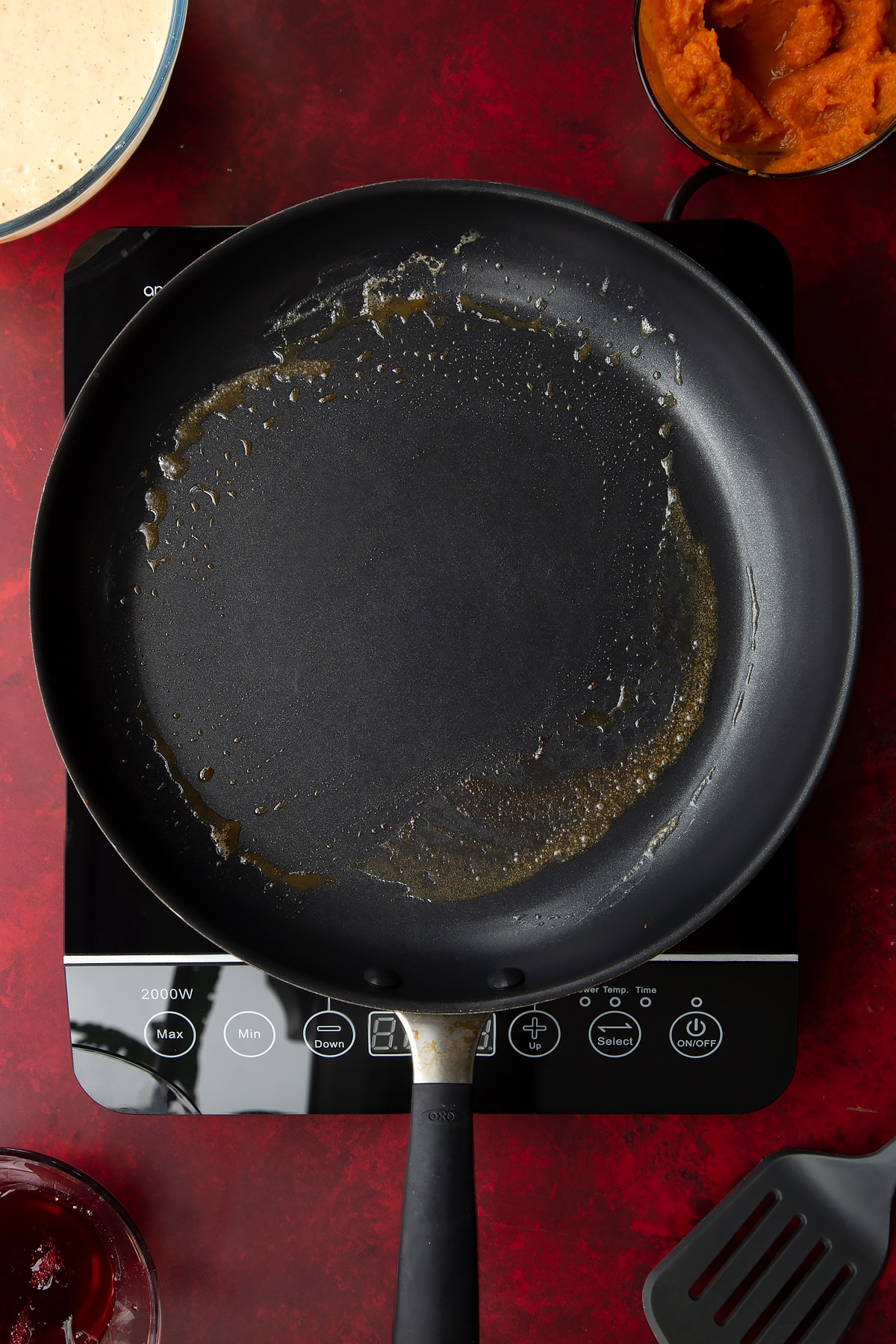 A greased frying pan. Ingredients to make Halloween pancakes surround the pan.