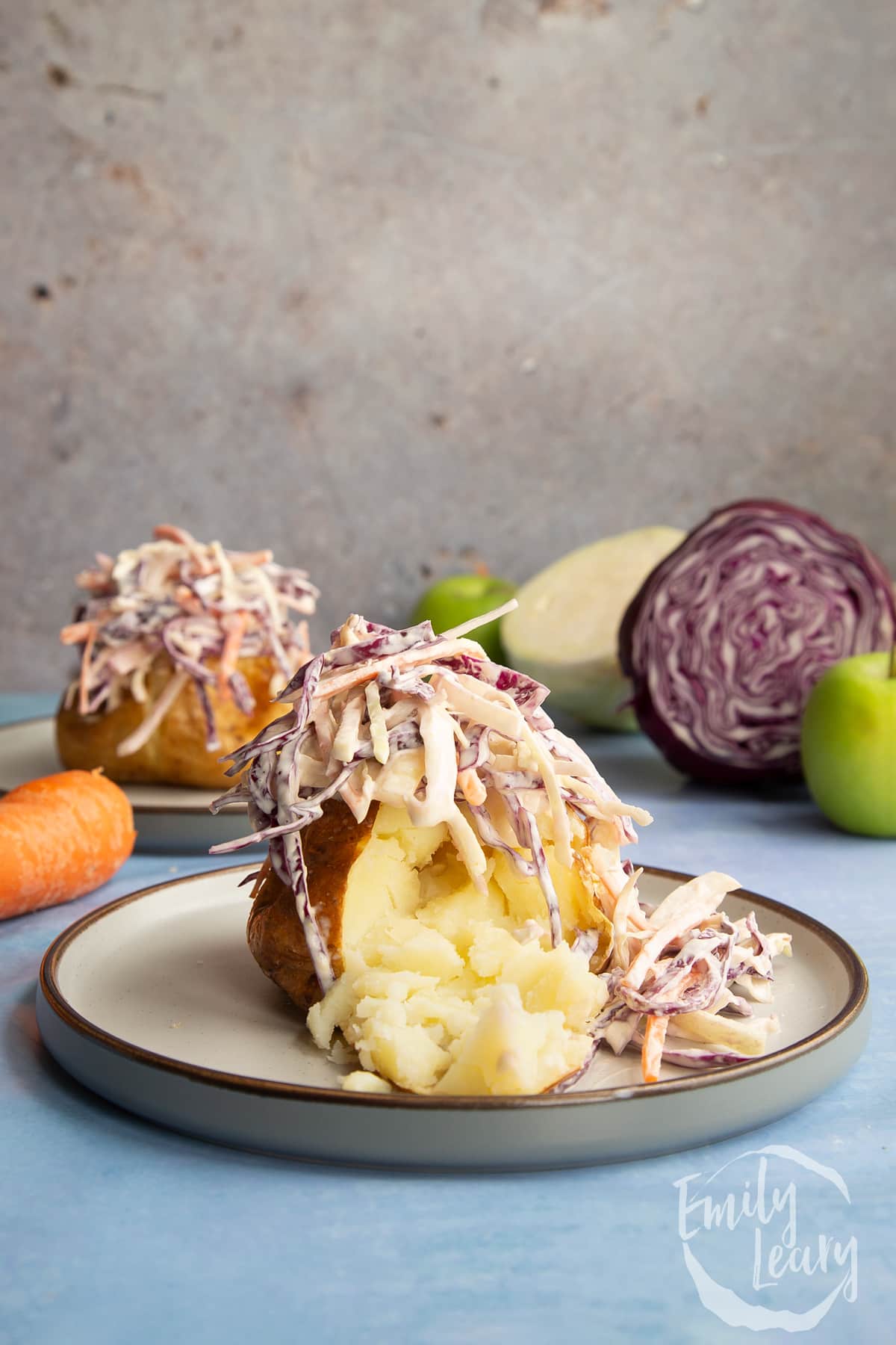 Jacket potato with cut open with homemade coleslaw on a plate.