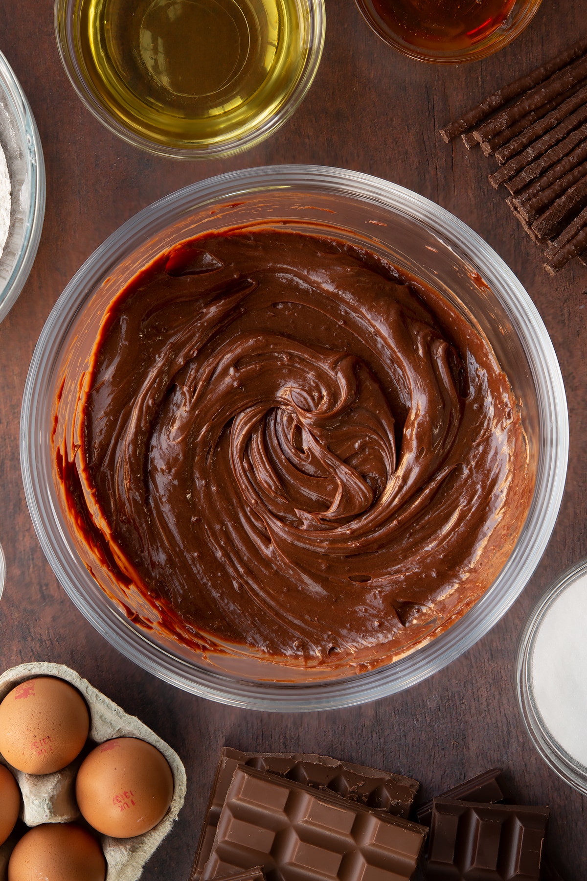 Matchmaker ganache in a glass mixing bowl. Ingredients to make Matchmaker cake surround the bowl.