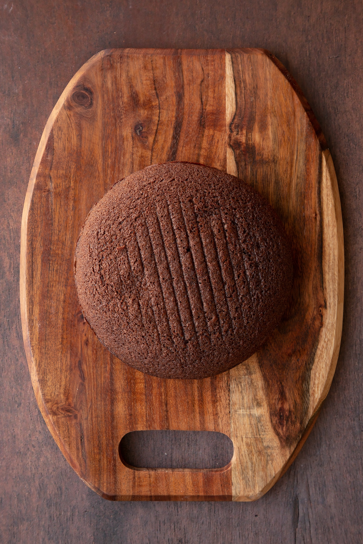 One chocolate cake on a wooden board.