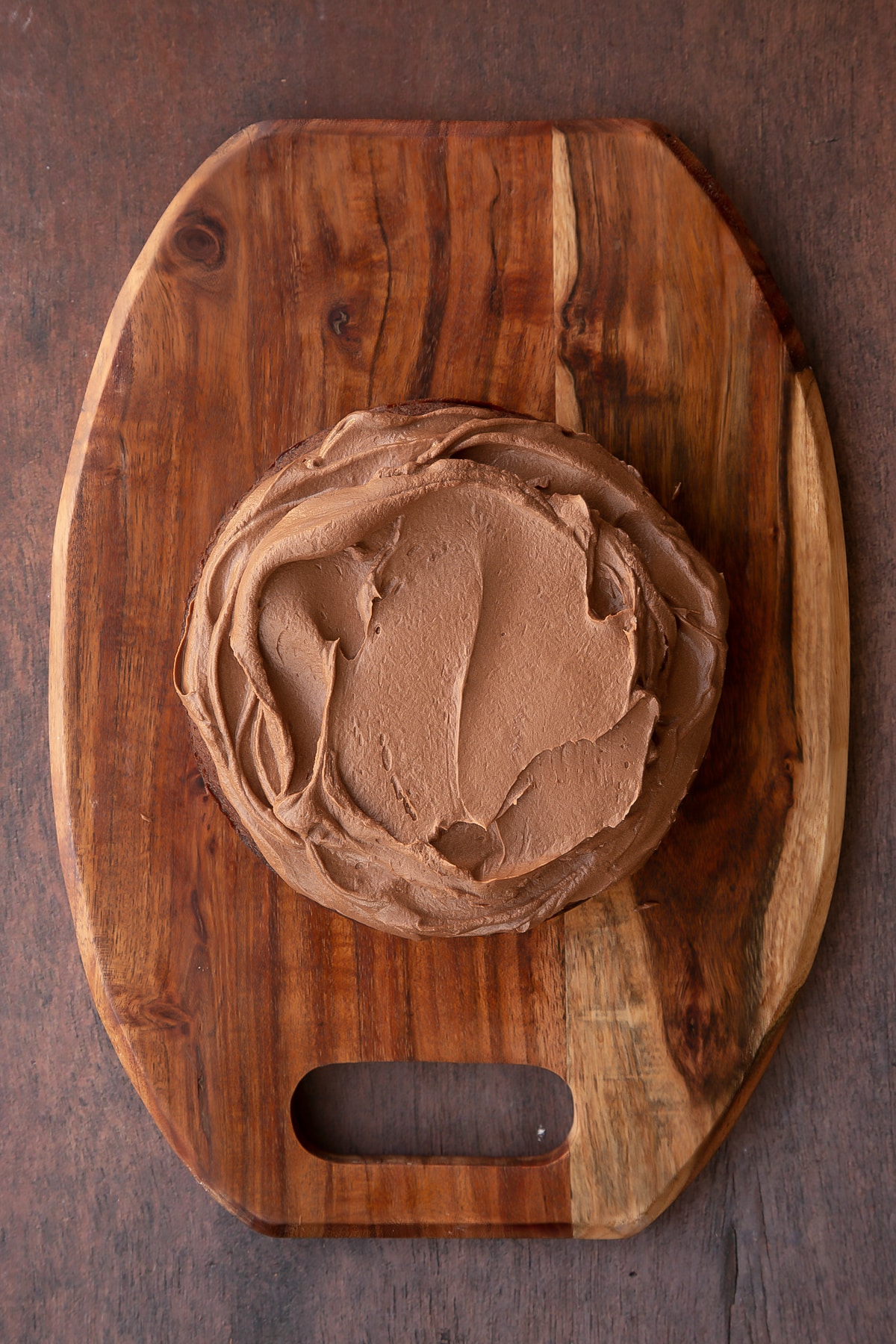 One chocolate cake on a wooden board, spread with Matchmaker ganache.