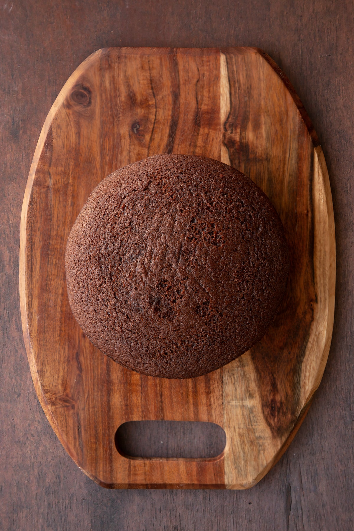 Two chocolate cake layers on a wooden board, sandwiched with Matchmaker ganache.