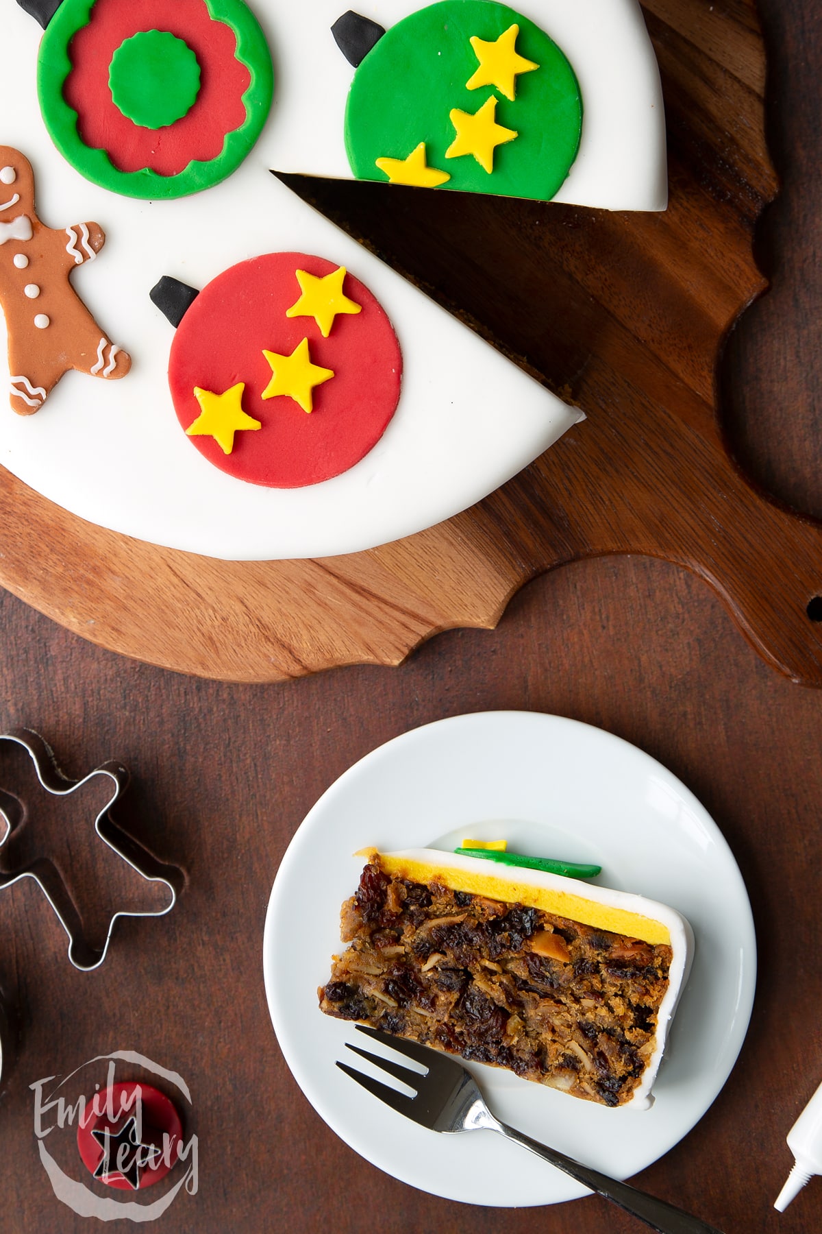 Slice of vegan Christmas cake laying on its side on a white plate with a fork. Shown from above.