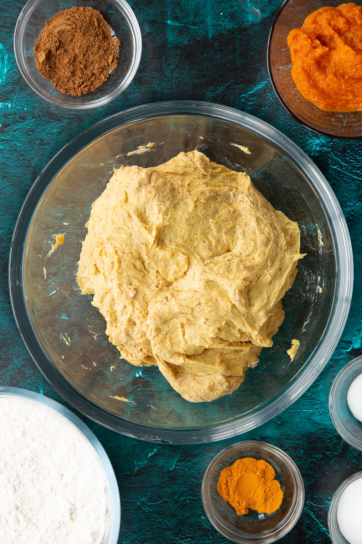 Pumpkin sourdough in a bowl. Ingredients to make pumpkin sourdough bread surround the bowl.