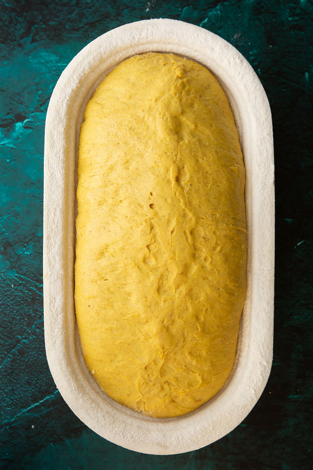 Pumpkin sourdough risen in floured proving basket.
