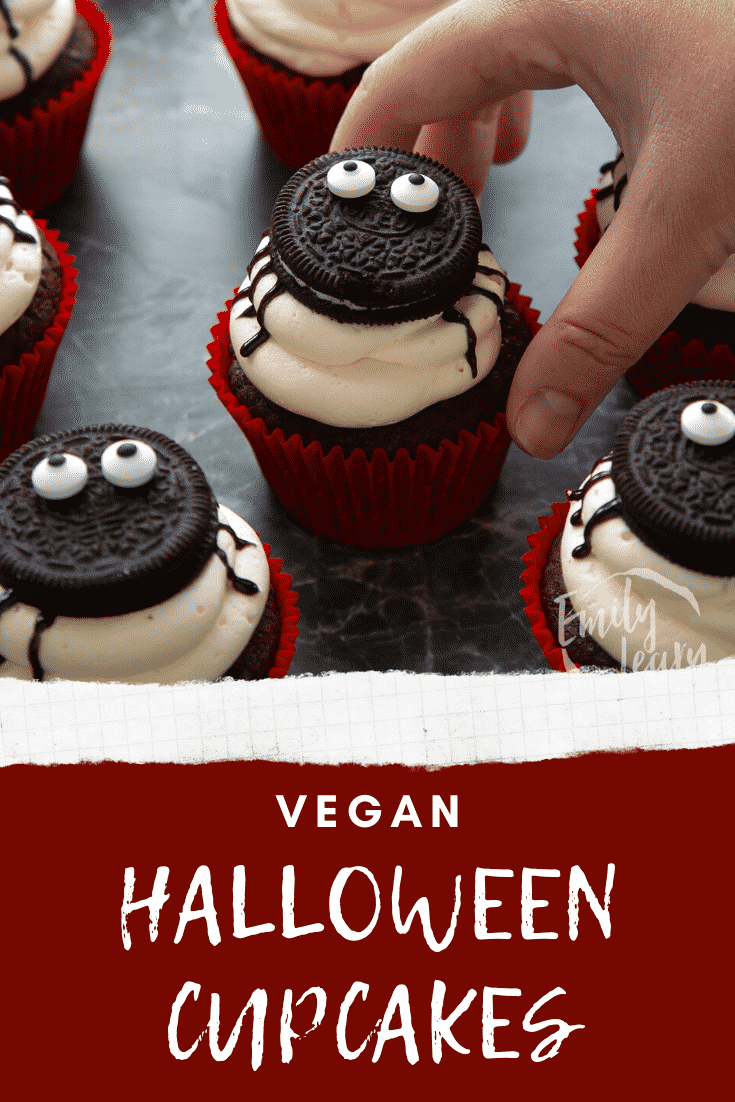 Vegan Halloween cupcakes, decorated with Oreos to look like spiders. A hand reaches for one. Caption reads: Vegan Halloween cupcakes.