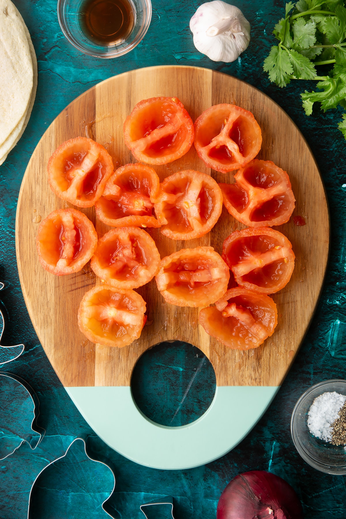 Peeled tomatoes, cut in half and deseeded on a wooden board.