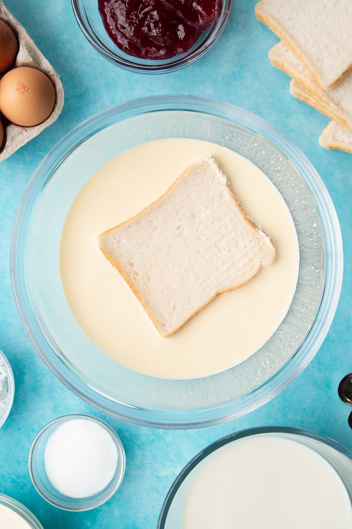 Soaking the slice of bread in the wet batter for the bread and butter pudding with jam.