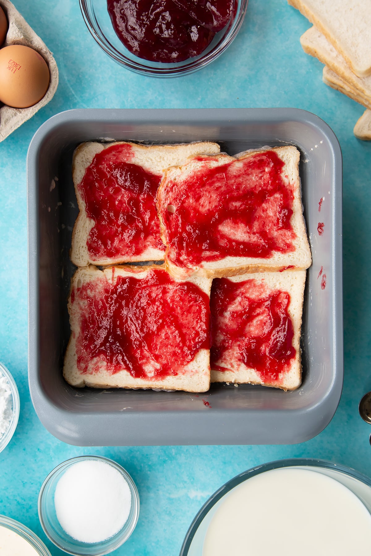 Layering the jam ontop of the bread in the baking dish.