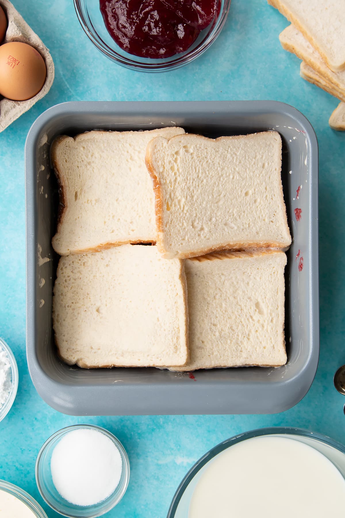 Adding a second layer of bread ontop of the jam inside the baking dish.