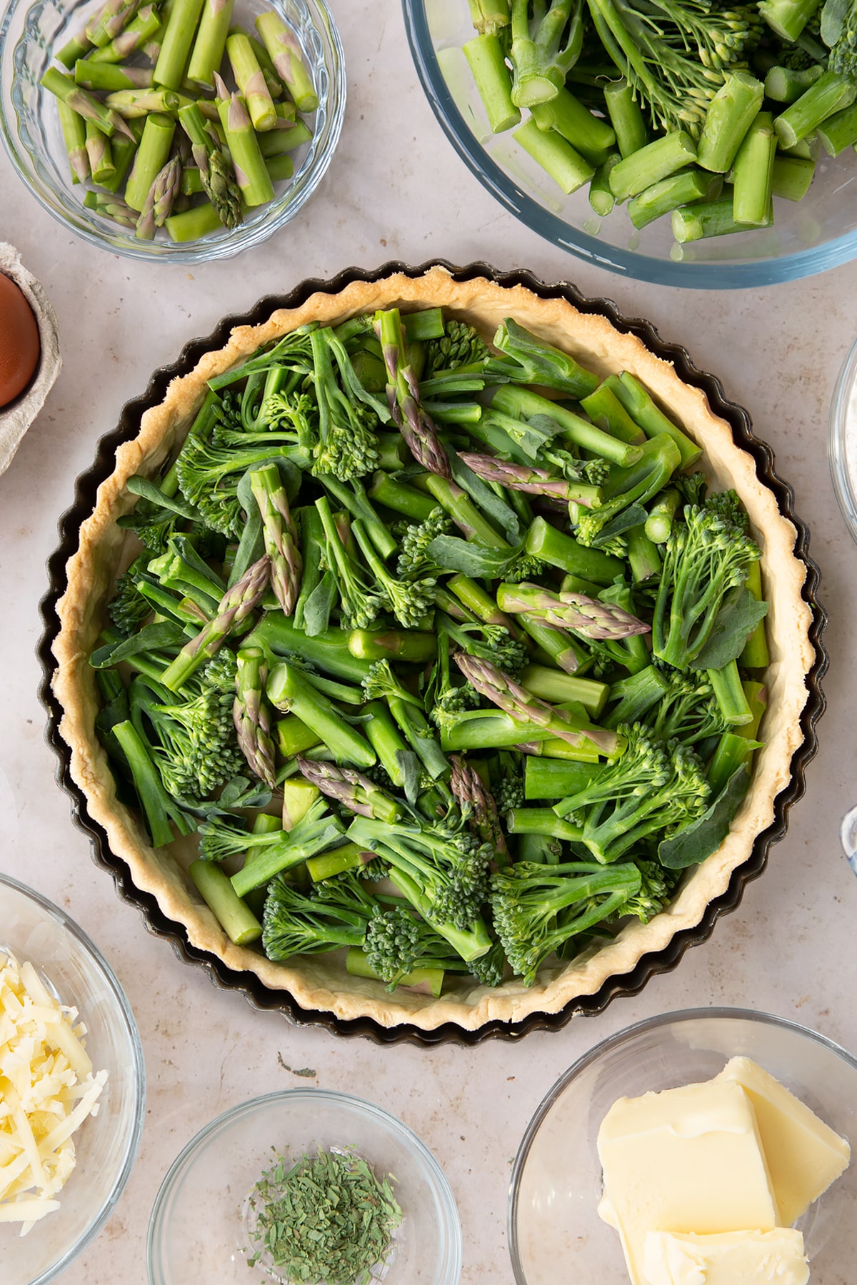 Overhead shot of adding the asaparagus, brocoli and beans to the pastry tin.