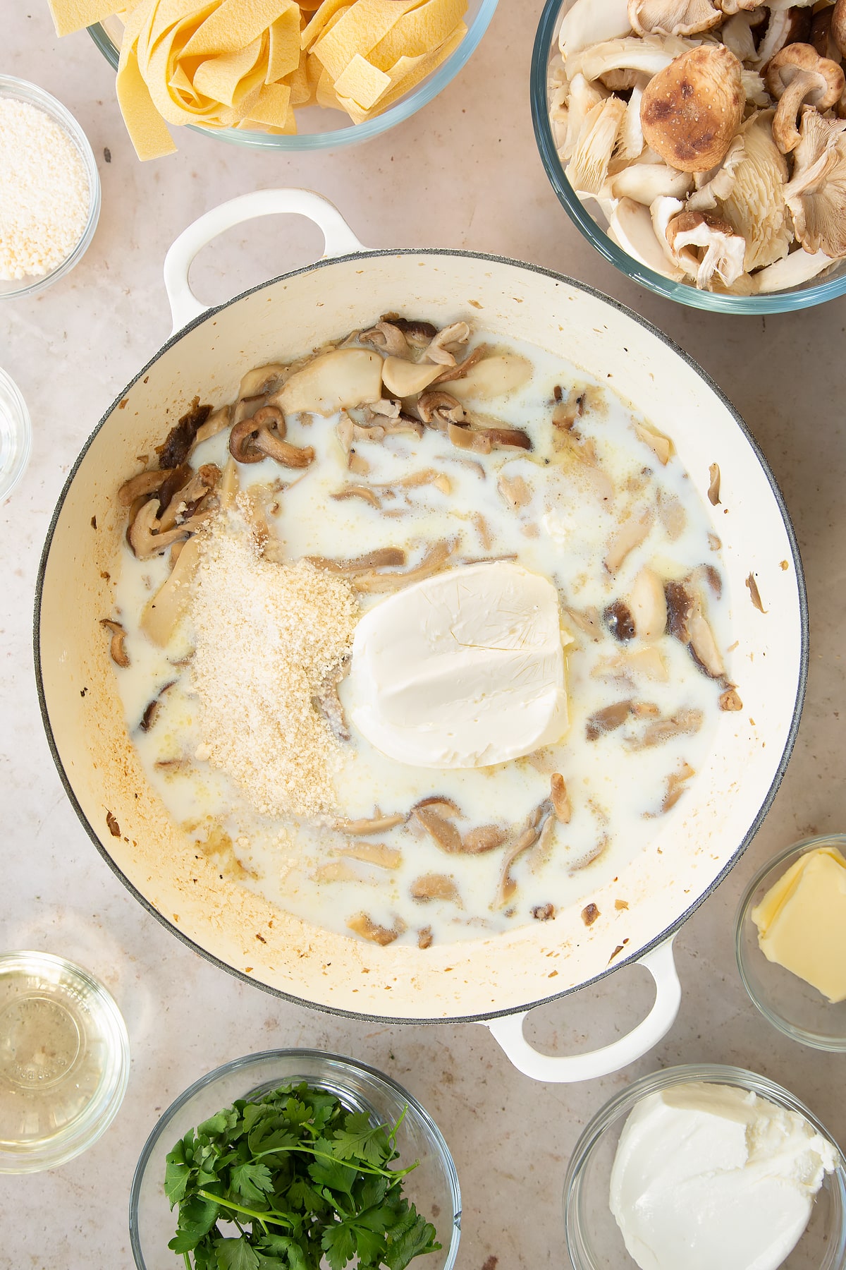 cooked mushroom mix topped with cream cheese and Parmesan in a large pan.