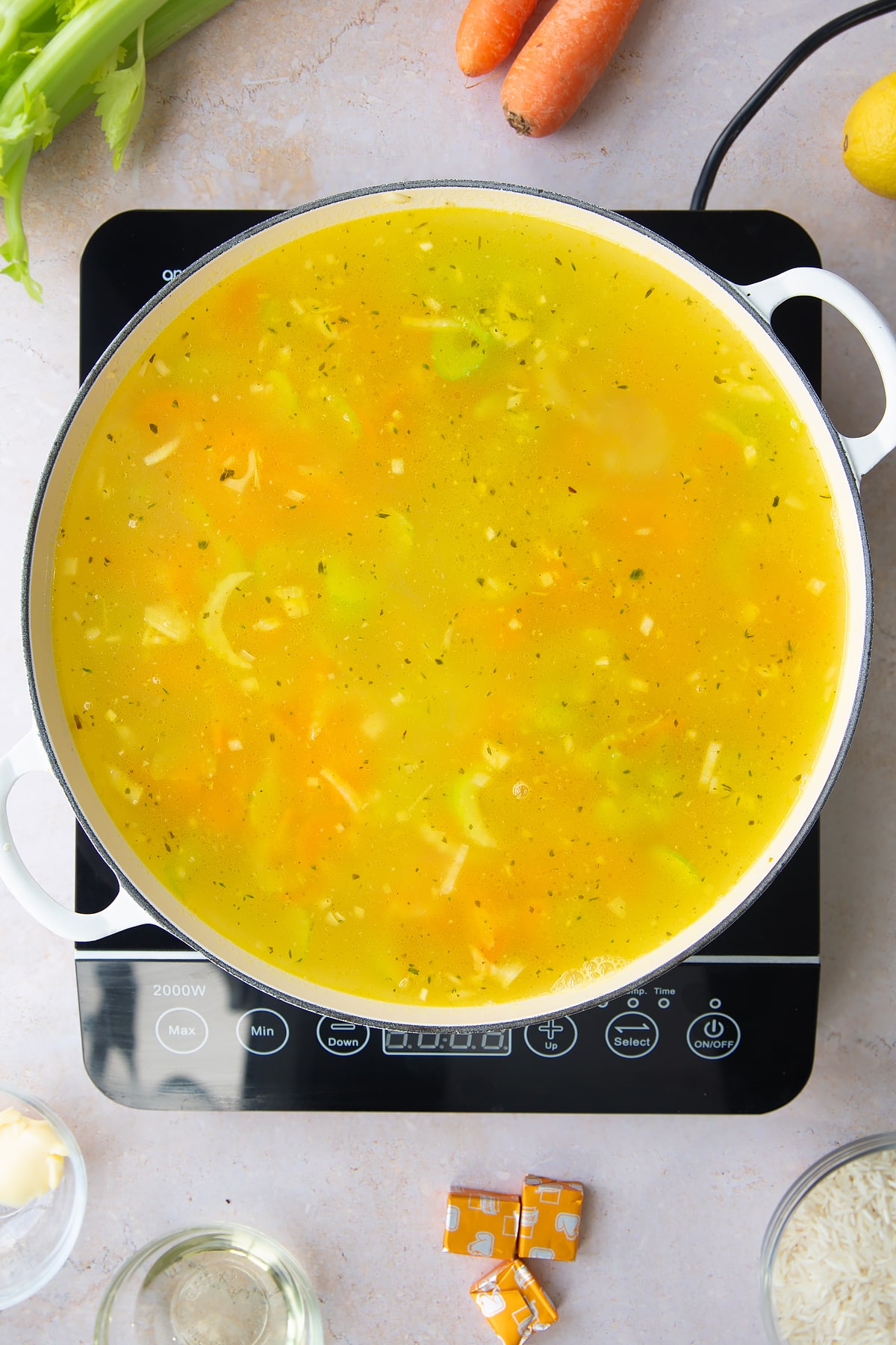 Overhead shot of the stock being added to the pan of ingredients for the turkey rice soup.