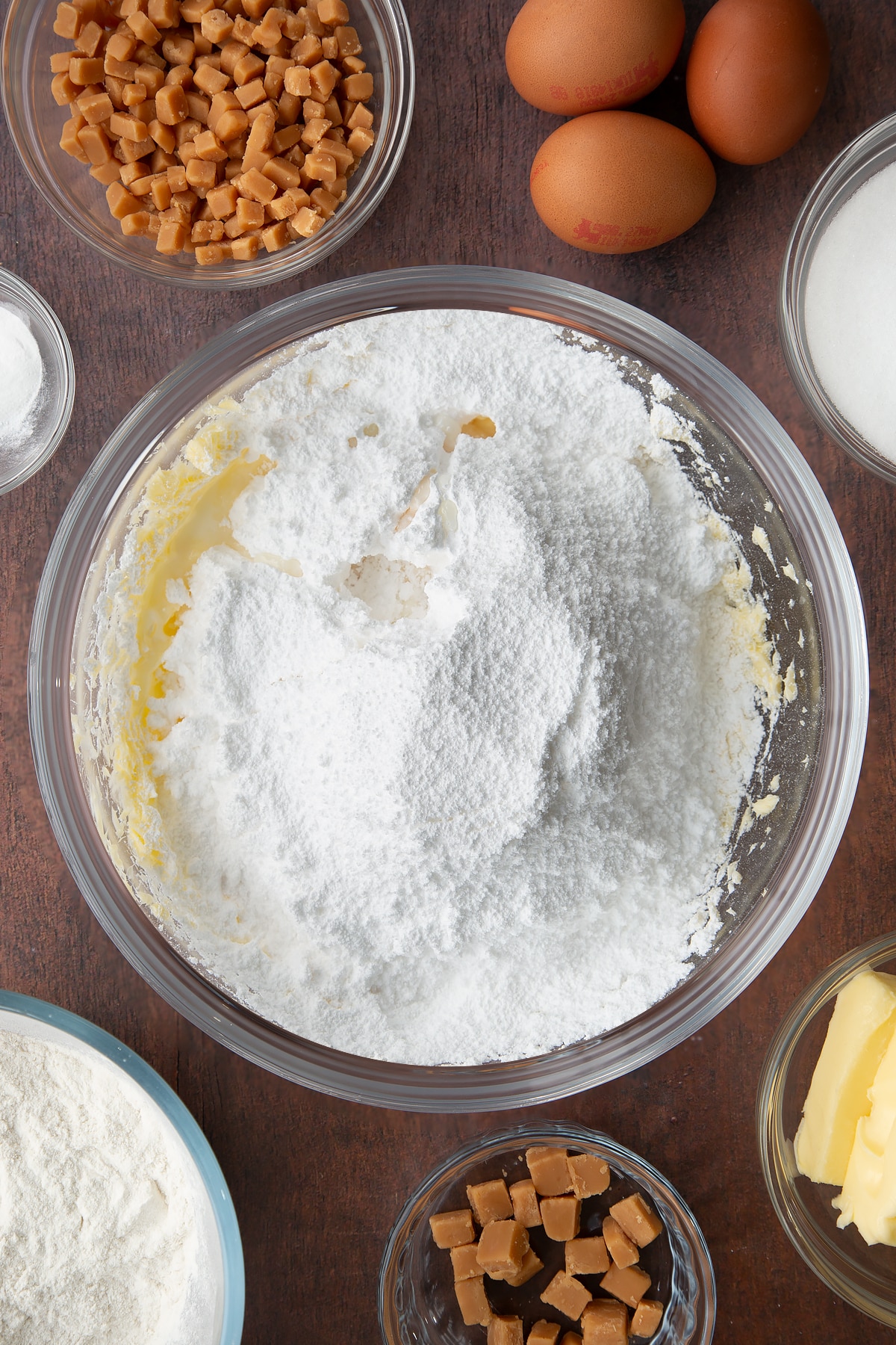 softened and beaten butter in a large clear bowl topped with icing sugar.