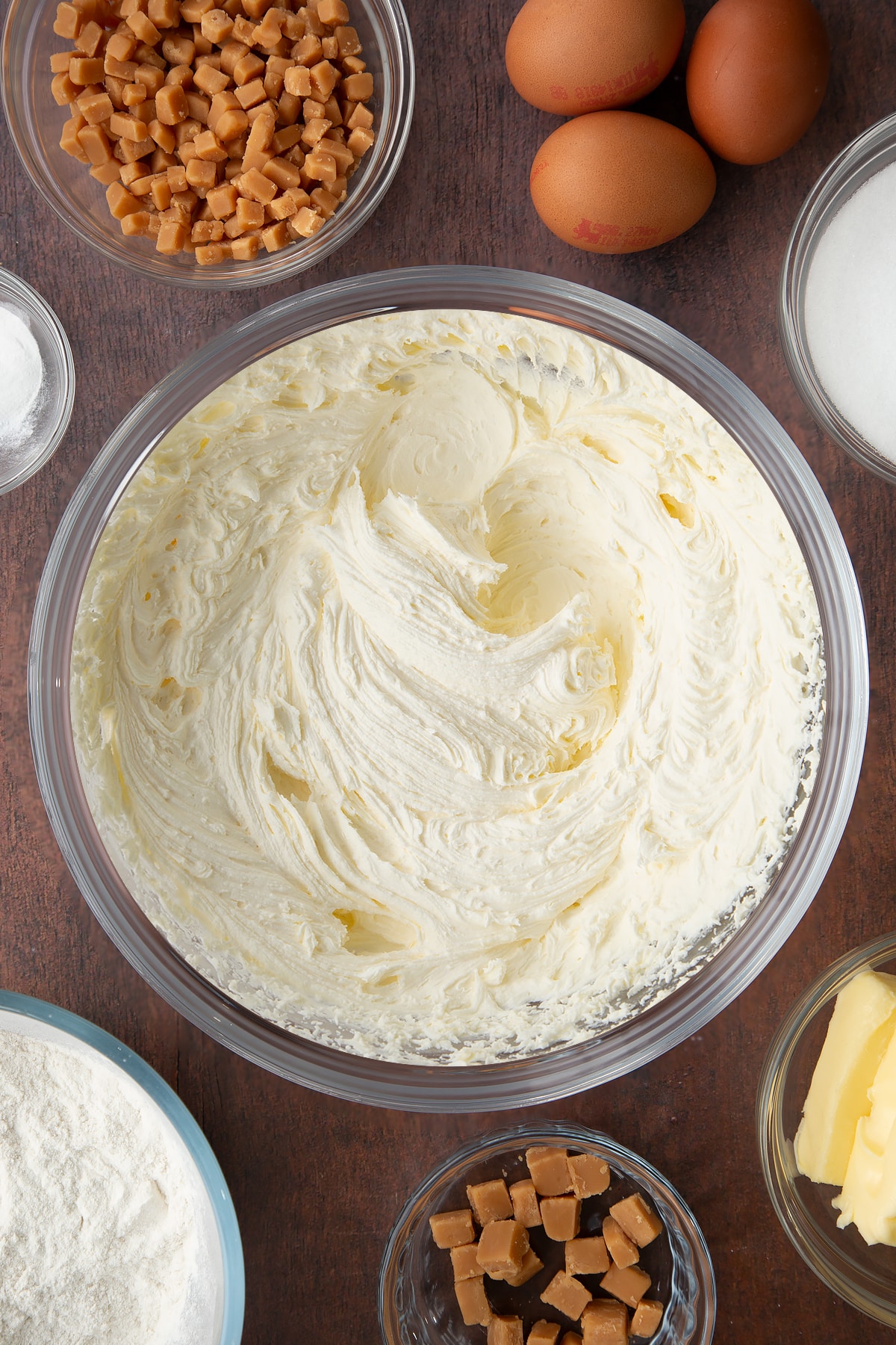 whisked buttercream topping in a large clear bowl.