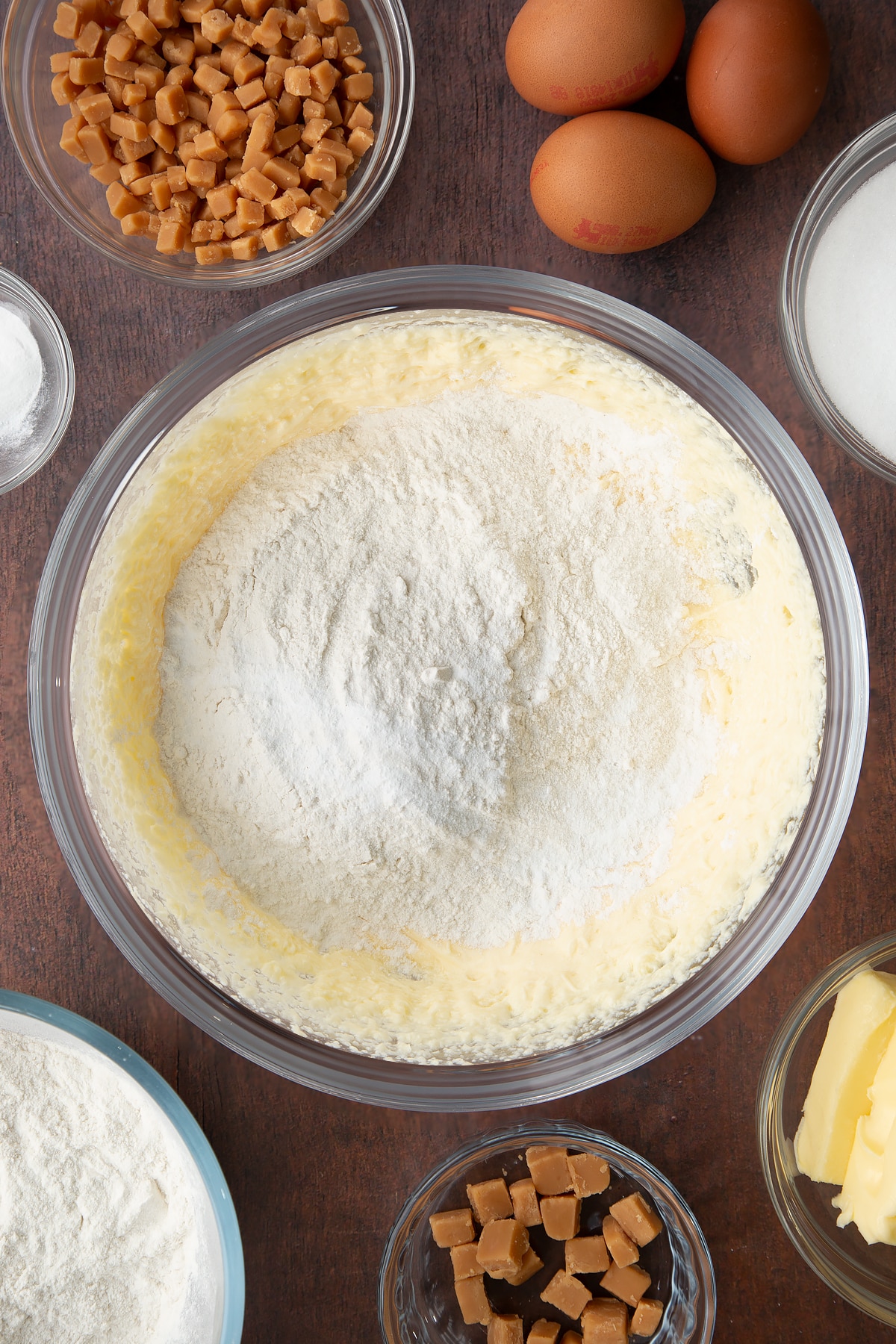 whisked yellow vanilla cake batter in. large clear bowl topped with baking powder and flour.