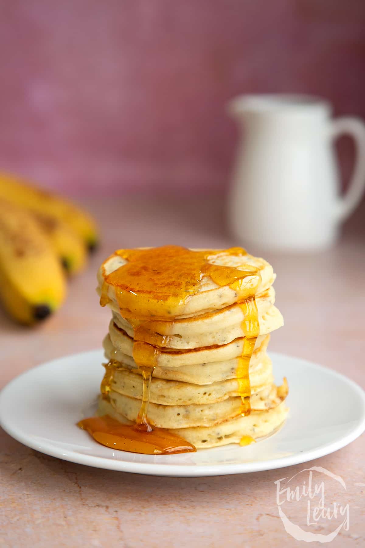 A stack of vegan chia pancakes on a small white plate, drizzled with golden syrup.