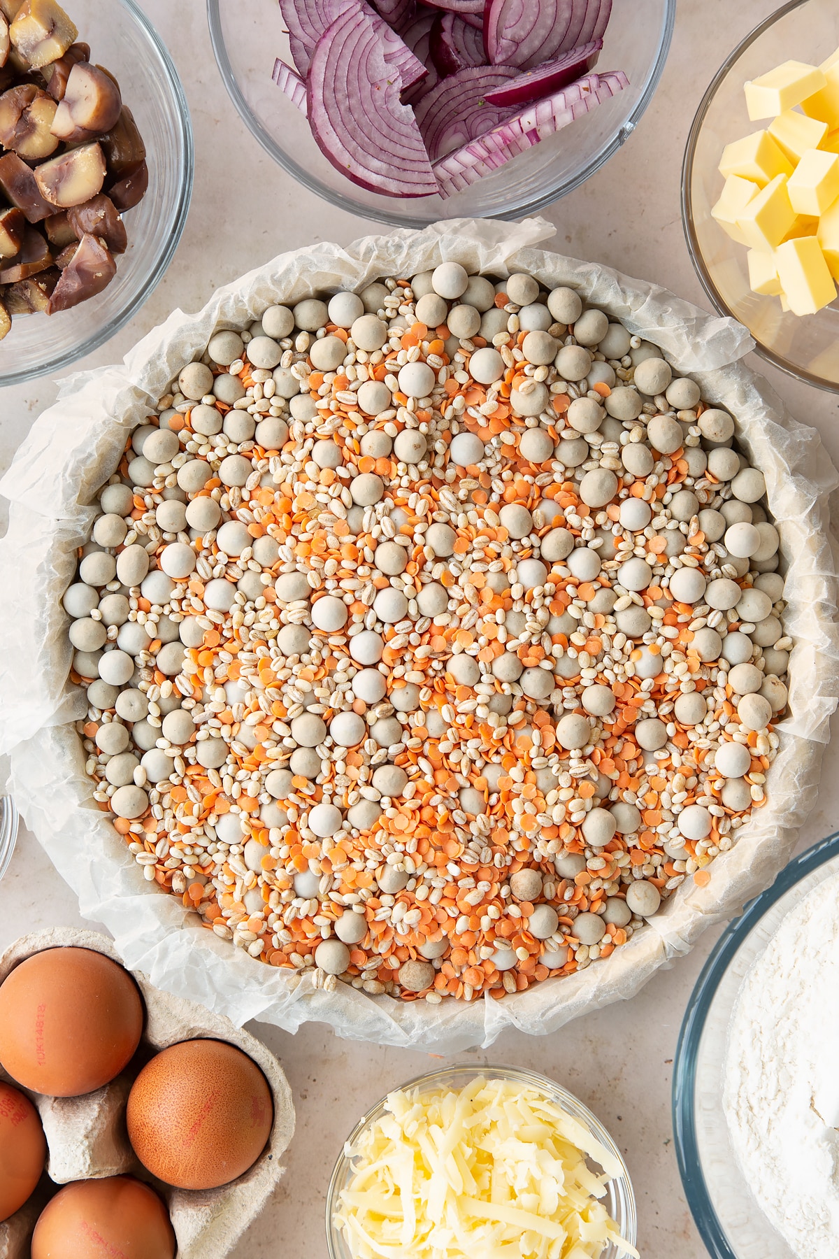 Overhead shot of the pastry inside the pie tin being worked in with baking beans.
