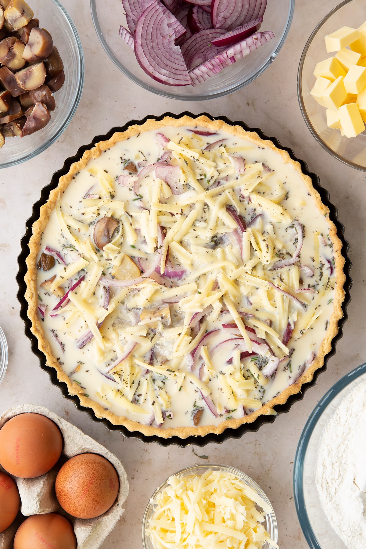 Overhead shot of the milk and eggs mixture having been poured onto the chestnut quiche mixtured inside a pie tin.