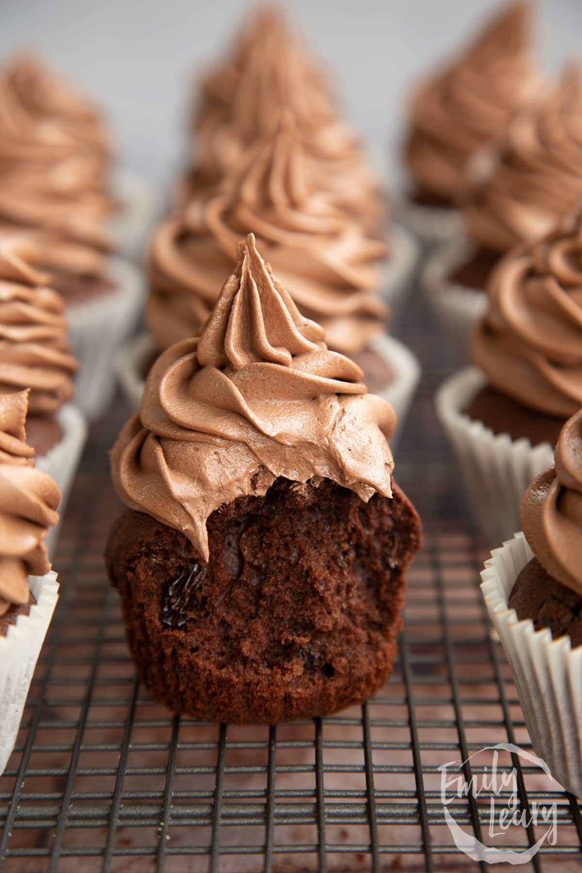 Chocolate raisin muffins on a wire rack. The muffin in the fore is unwrapped with a bite out of it.