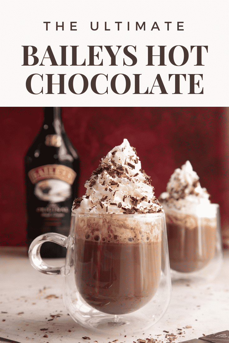 Two mugs of a rich Baileys hot chocolate recipe, topped with whipped cream and chocolate shavings. Caption reads: The ultimate Baileys hot chocolate.