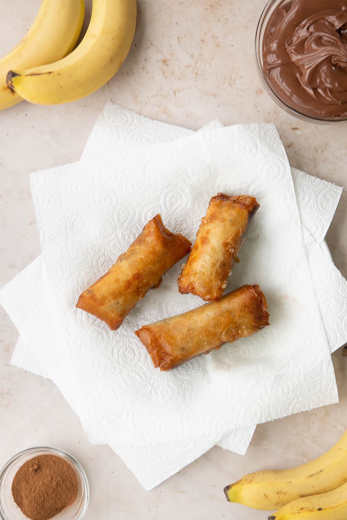 Overhead shot of the fried banana chocolate spring rolls cooling on paper towels.