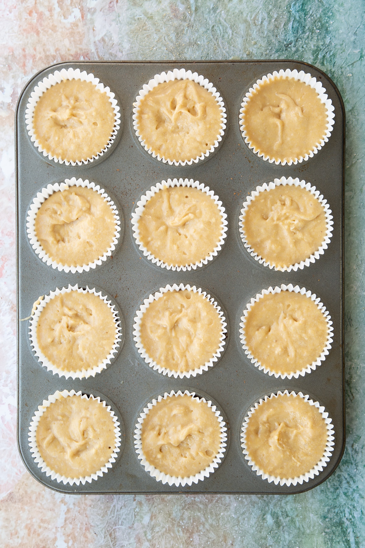 Banana cornmeal muffin batter in a muffin tray.