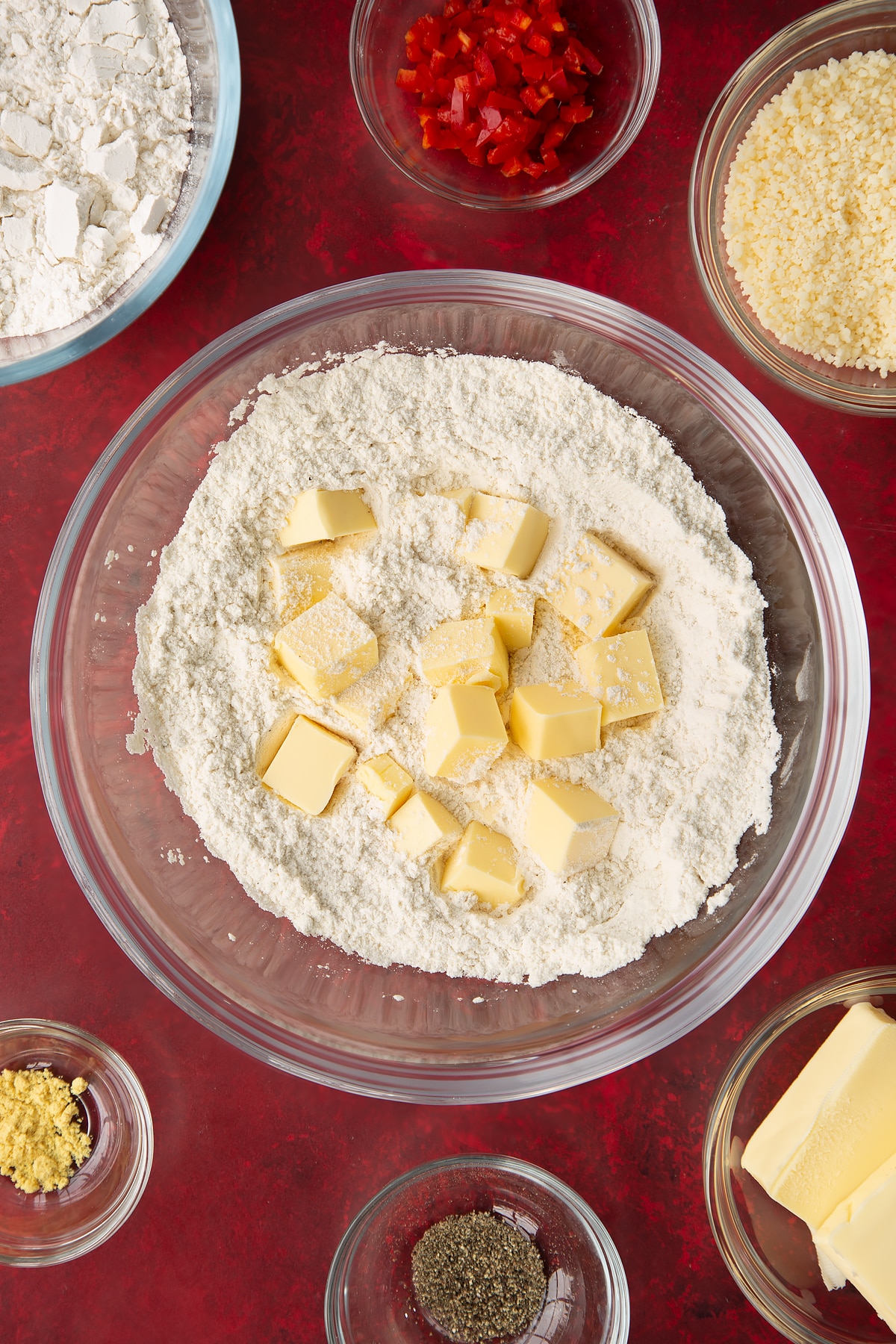 Adding the butter to the dry ingredients for the spicy cheese straws in a mixing bowl.