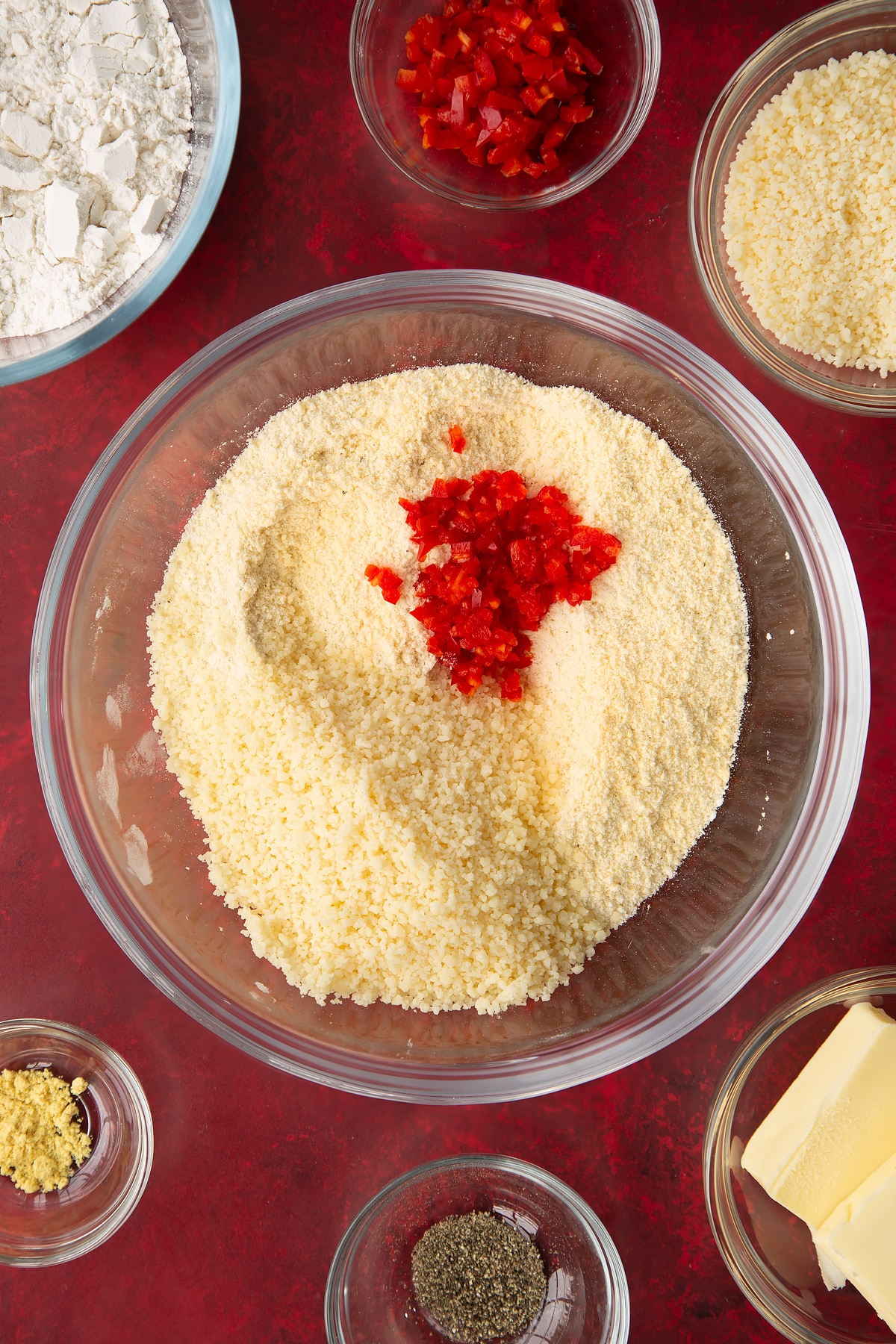Adding the finely grated cheese and chopped chilis to the spicy cheese straws dry mixture.
